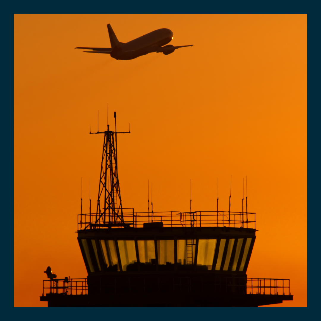 A promotional graphic set within a dark blue frame showing a silhouette of an airplane taking off over an airport control tower against an orange sunset sky.