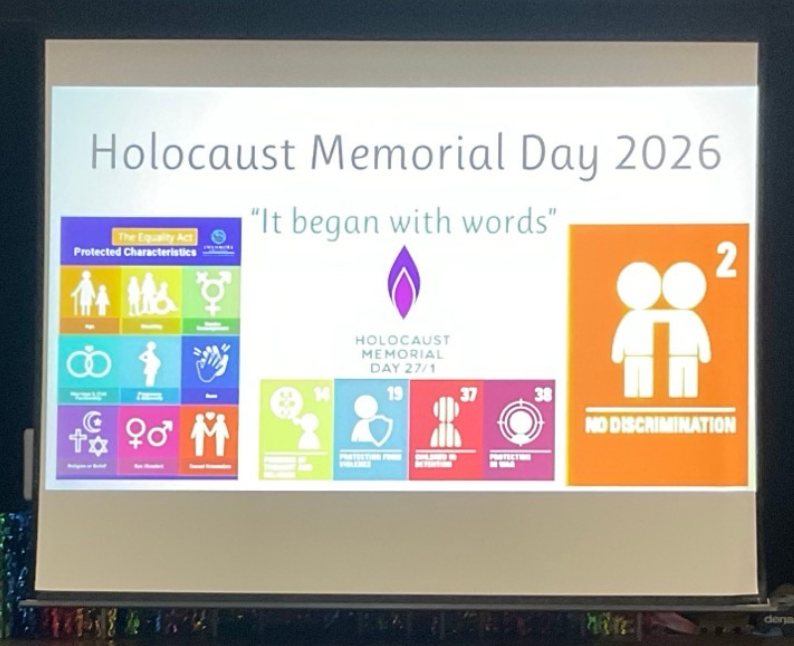 Image shows a projected presentation slide reading “Holocaust Memorial Day 2026” and “It began with words,” alongside icons representing protected characteristics, equality, and human rights.