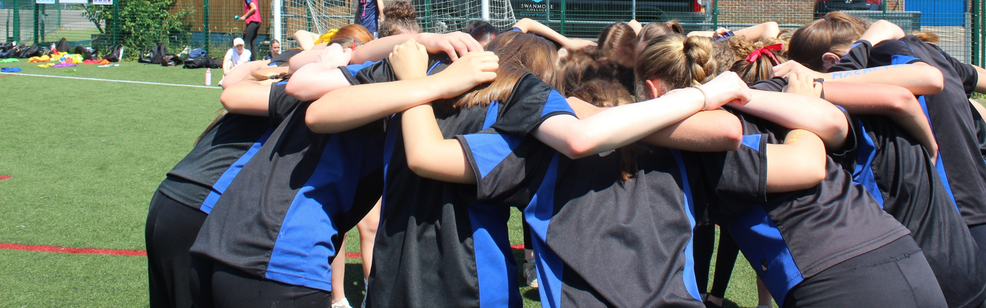 Image shows pupils in a huddle on one of the sports pitches