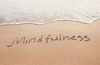 Image shows a photo of the word Mindfulness written in the sand with a small wave approaching