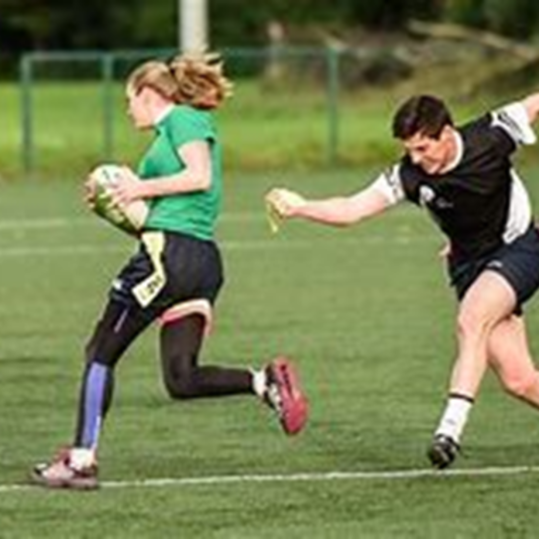 Image shows 2 people playing tag rugby - a tag has been taken from the player with the ball