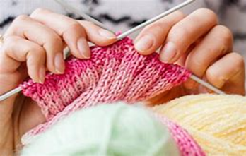 Image shows someone knitting a ribbed cuff in shades of pink