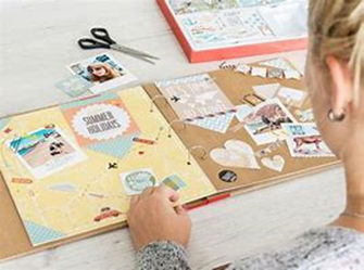 Image shows a person working at a table with a scrapbook in front of them and pictures to cut out