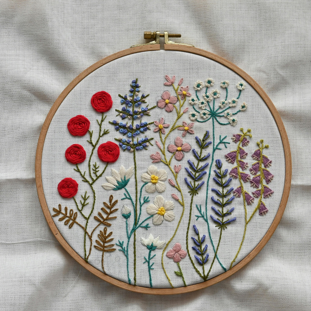 Image shows embroidery canvas in a hoop with flowers made with different embroidery stitches