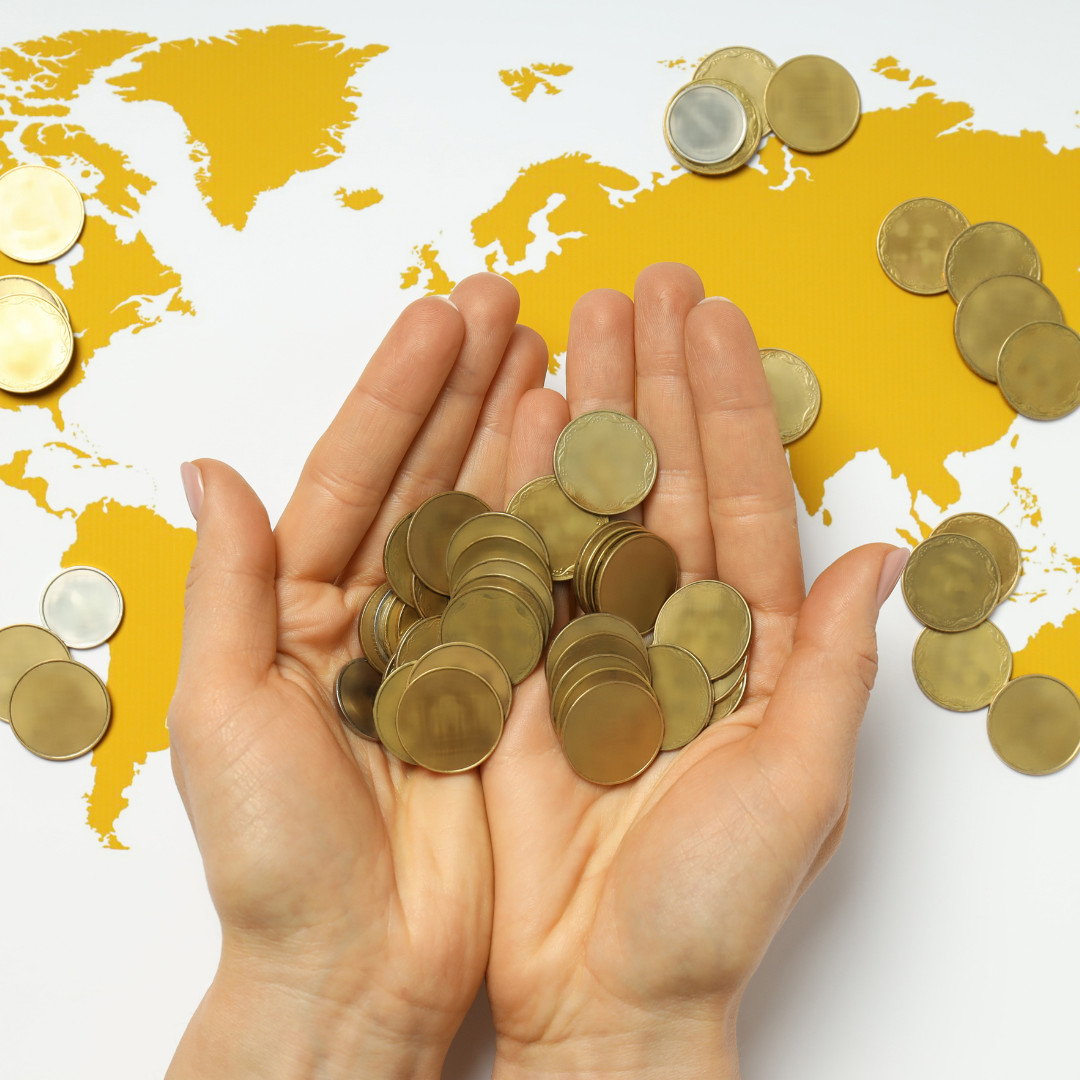 Image shows a pair of hands holding gold coins above a map of the world