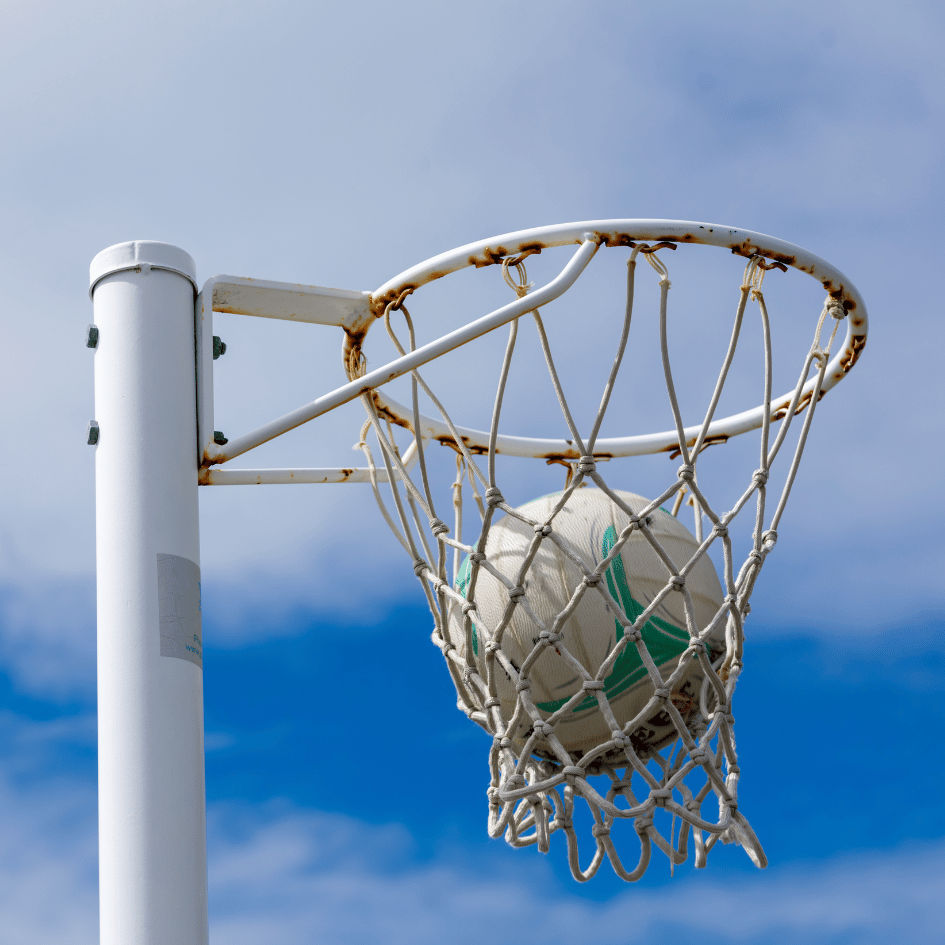 Image shows a netball in a net against a blue sky.