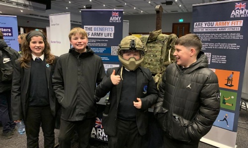 A group of pupils from Swanmore standing and smiling at the British Army stand at the Get Inspired Portsmouth careers event