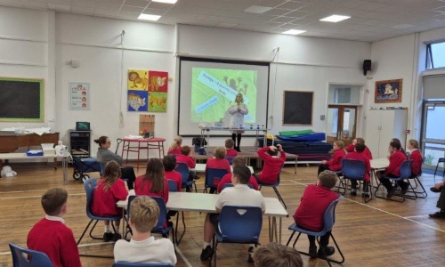 Science teacher standing in front of a projected slide titled “Biology – A Journey Around Our Body” while delivering the science show.
