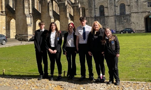 Year 10 pupils in school uniform standing outside Winchester Cathedral on a sunny day during their Religious Studies trip.