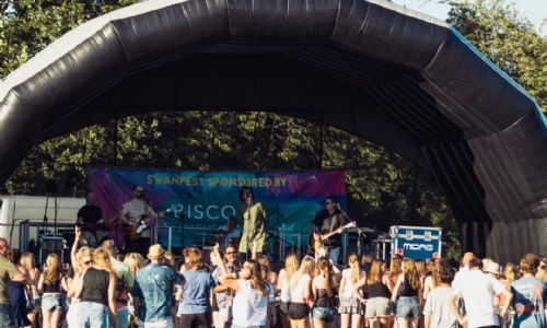 Wide shot of the main stage at SwanFest with audience gathered in front. 